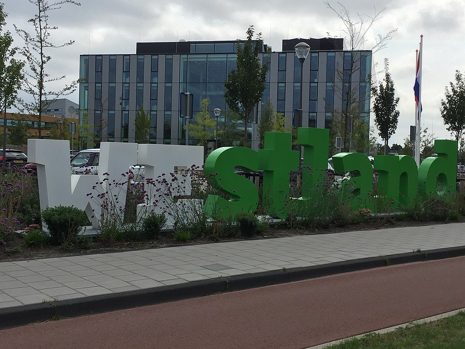 Verhuisbedrijf Westland - stadsbeeld met grote groene en witte Westland-letters en modern kantoorgebouw op de achtergrond